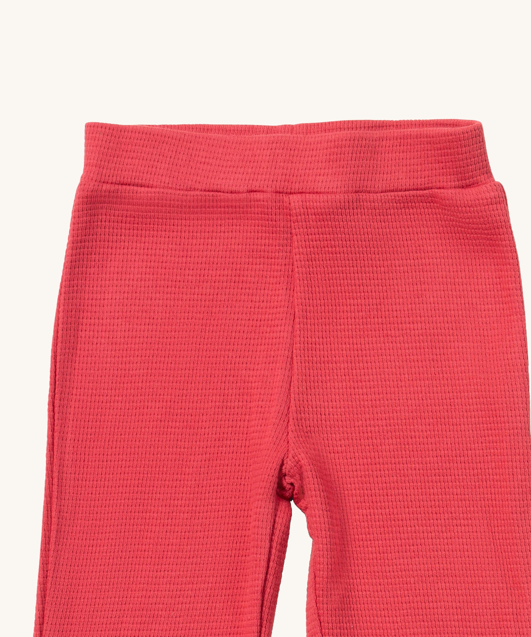 A close up of the Little Green Radicals pink berry waffle leggings showing the waffle knit detail and elasticated waist band on pink organic cotton fabric