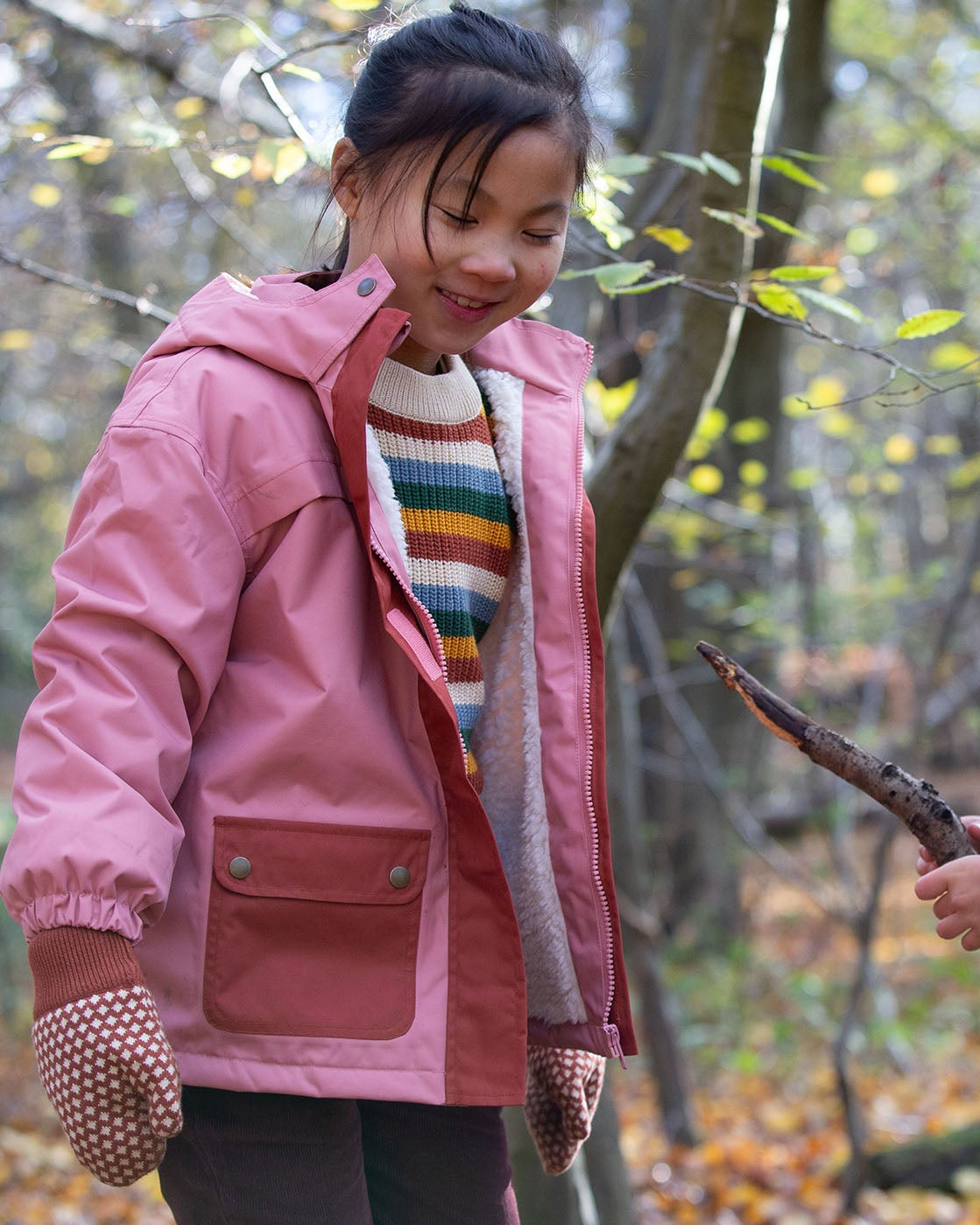 Two children playing with a stick while wearing little green radicals coats