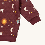 A close up of the Little Green Radicals flying birds quilted sweatshirt that's available at Babipur. Showing the quilted detail on dark maroon organic cotton fabric