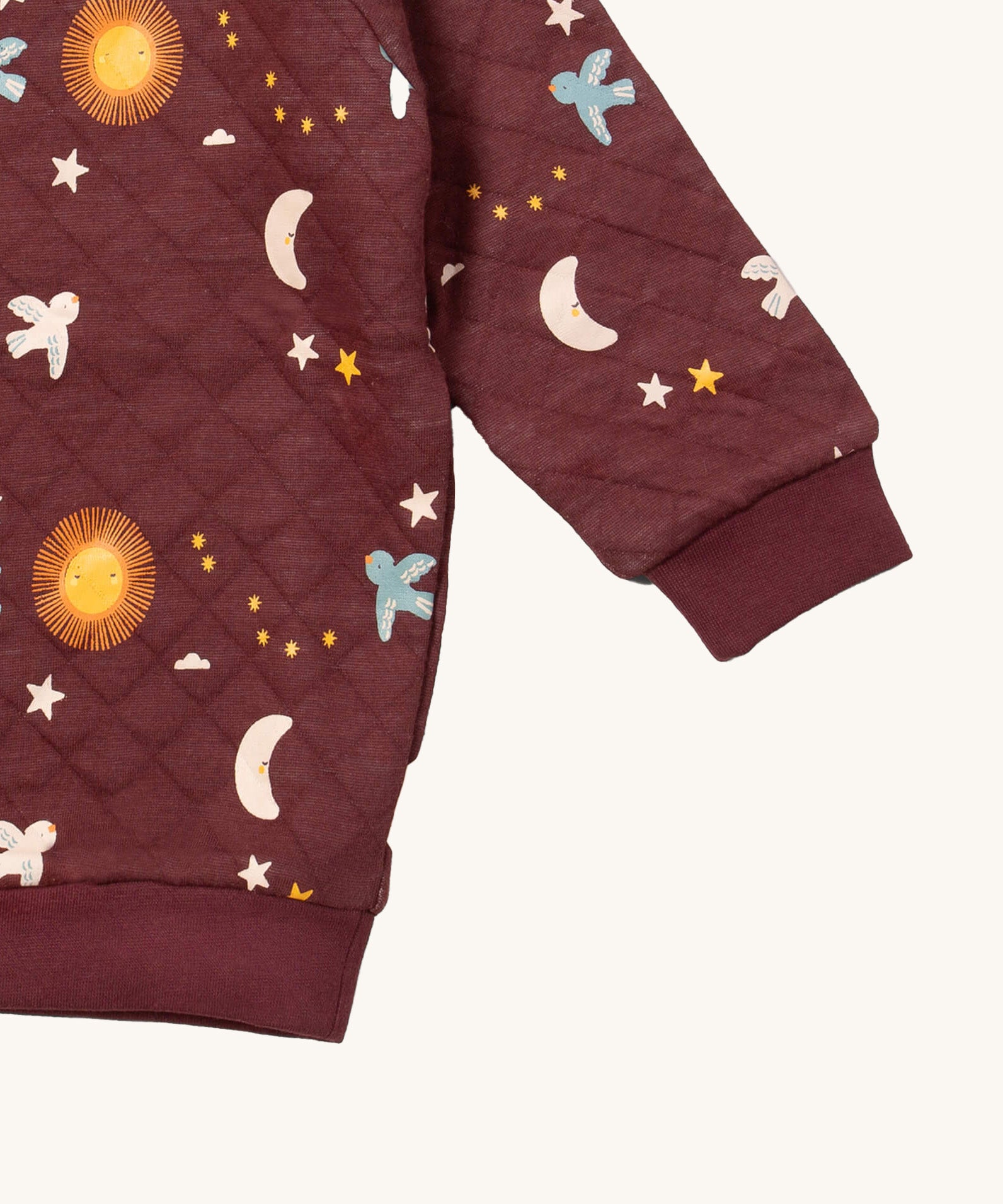 A close up of the Little Green Radicals flying birds quilted sweatshirt that's available at Babipur. Showing the quilted detail on dark maroon organic cotton fabric