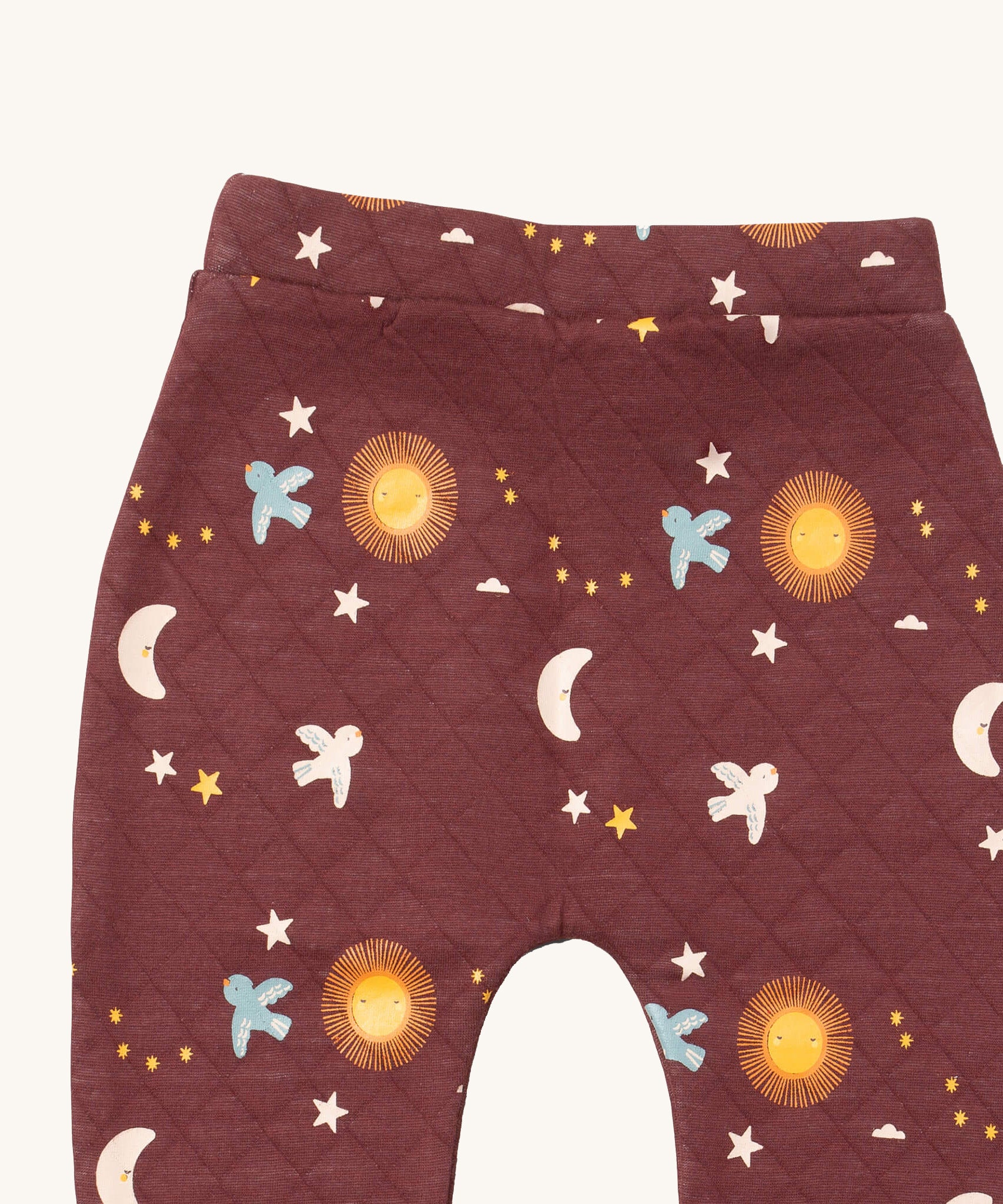 A close up of the Little Green Radicals flying birds quilted joggers. Showing the quilted stitch and flying prints detail on dark maroon organic cotton fabric.