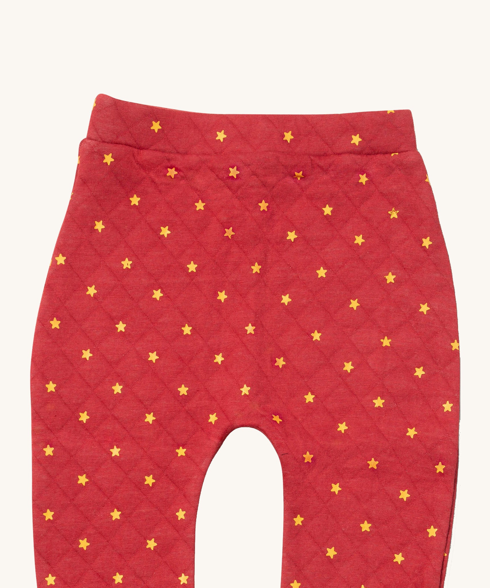 A close up of the Little Green Radicals red star quilted joggers. Showing the quilted stitch and yellow stars detail on red organic cotton fabric.