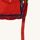 A close up of the Little Green Radicals ready for adventure backpack in dark night. Showing the front red pocket detail which features a button fastener on navy corduroy cotton fabric.