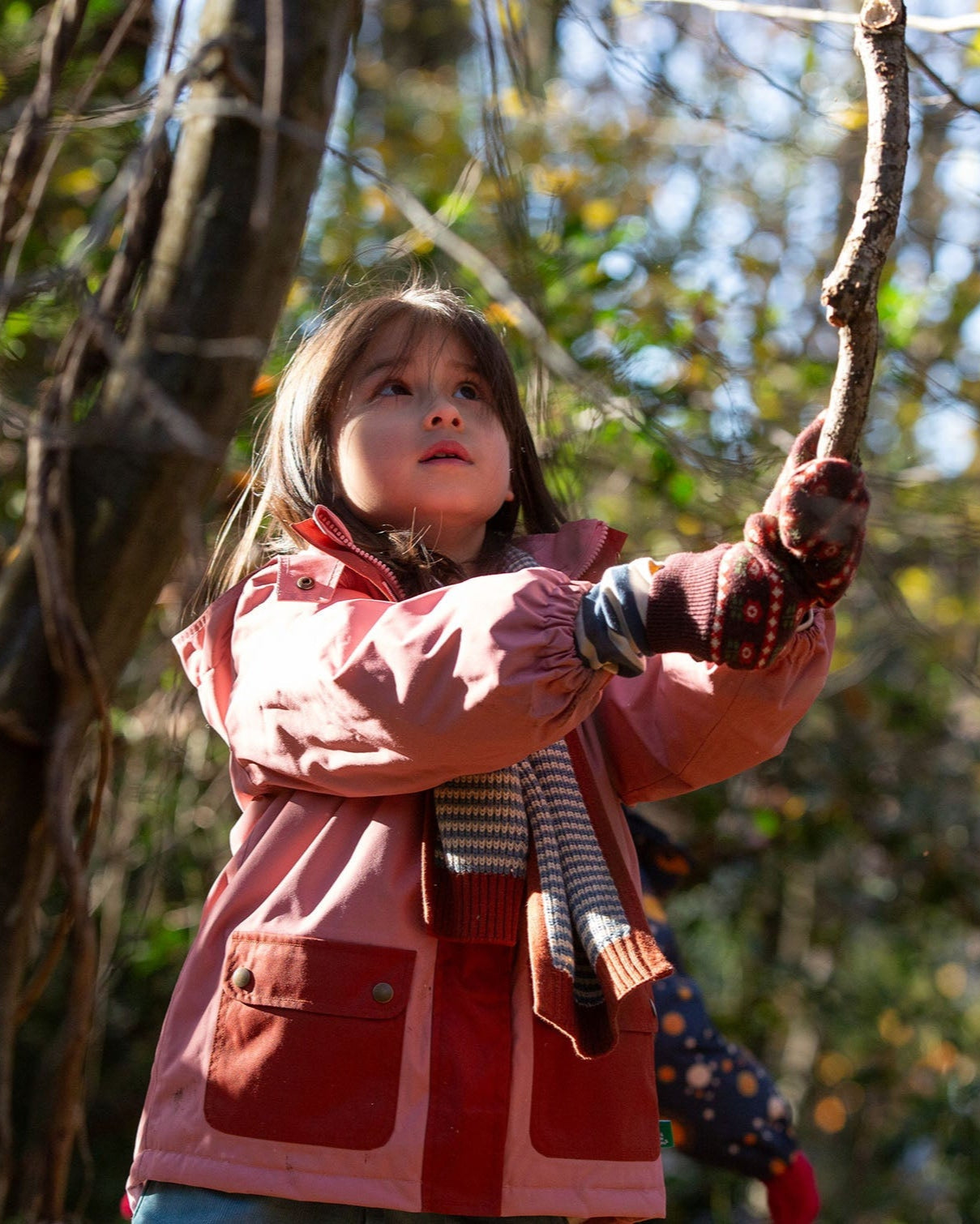 Child in a red coat playing with a rope in a natural setting