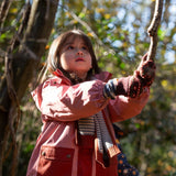 Child in a red coat playing with a rope in a natural setting