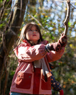 Child in a red coat playing with a rope in a natural setting