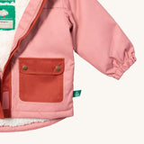 A close up of the Little Green Radicals waterproof coat in coral showing the elasticated cuff detail on pink recycled polyester fabric