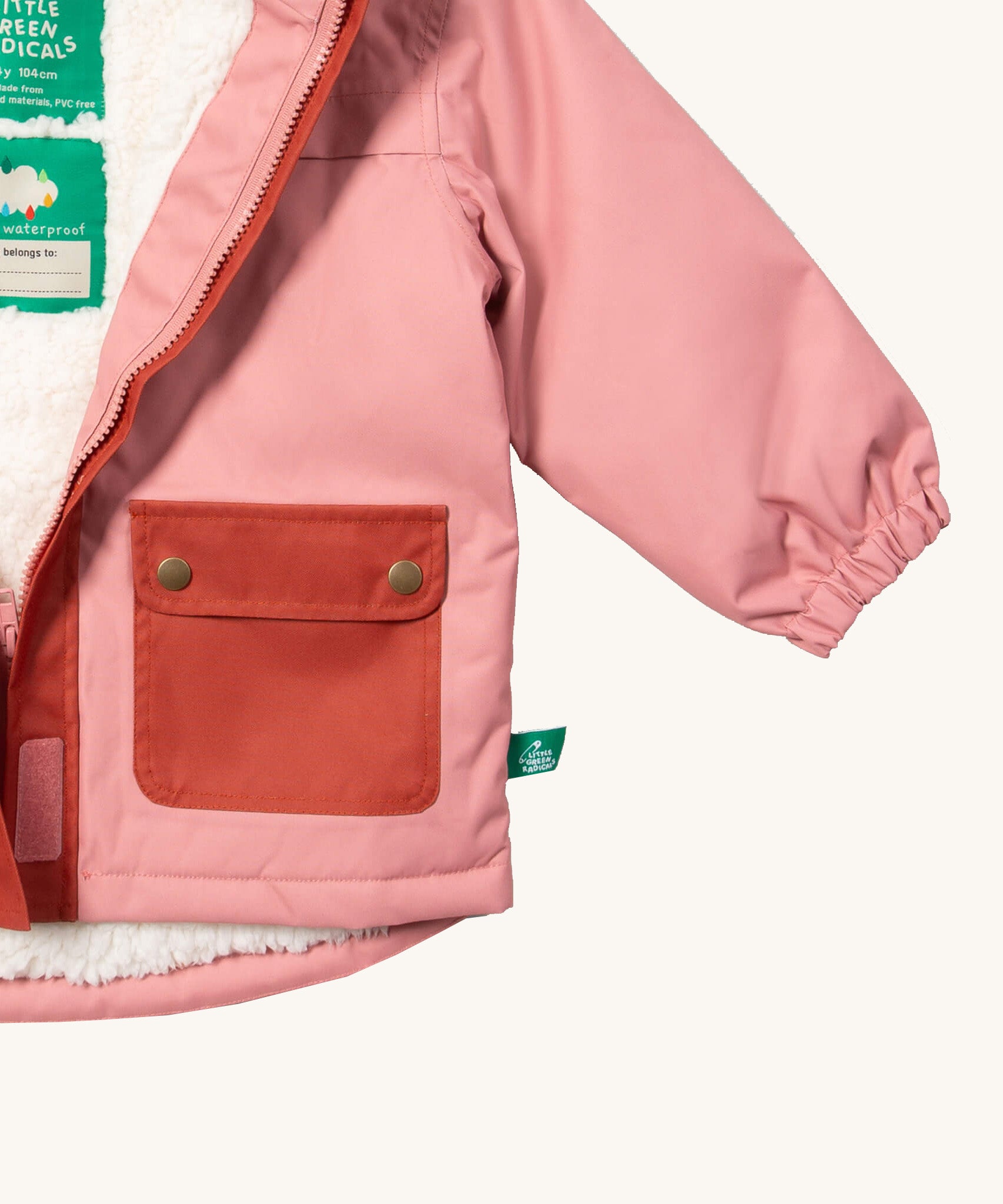 A close up of the Little Green Radicals waterproof coat in coral showing the elasticated cuff detail on pink recycled polyester fabric