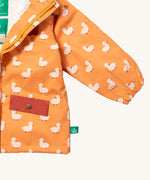 A close up of the Little Green Radicals waterproof coat in gold ducks showing the elasticated cuff detail on yellow recycled polyester fabric