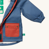 A close up of the Little Green Radicals waterproof coat in moonlight blue Showing the elasticated cuff detail on blue recycled polyester fabric