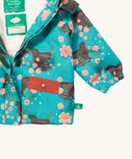 A close up of the Little Green Radicals waterproof coat in winter rabbits showing the sherpa fleece inner liner and full length zip detail on turquoise recycled polyester fabric