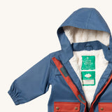 A close up of the Little Green Radicals waterproof coat in moonlight blue Showing the sherpa fleece liner and name patch detail on blue recycled polyester fabric