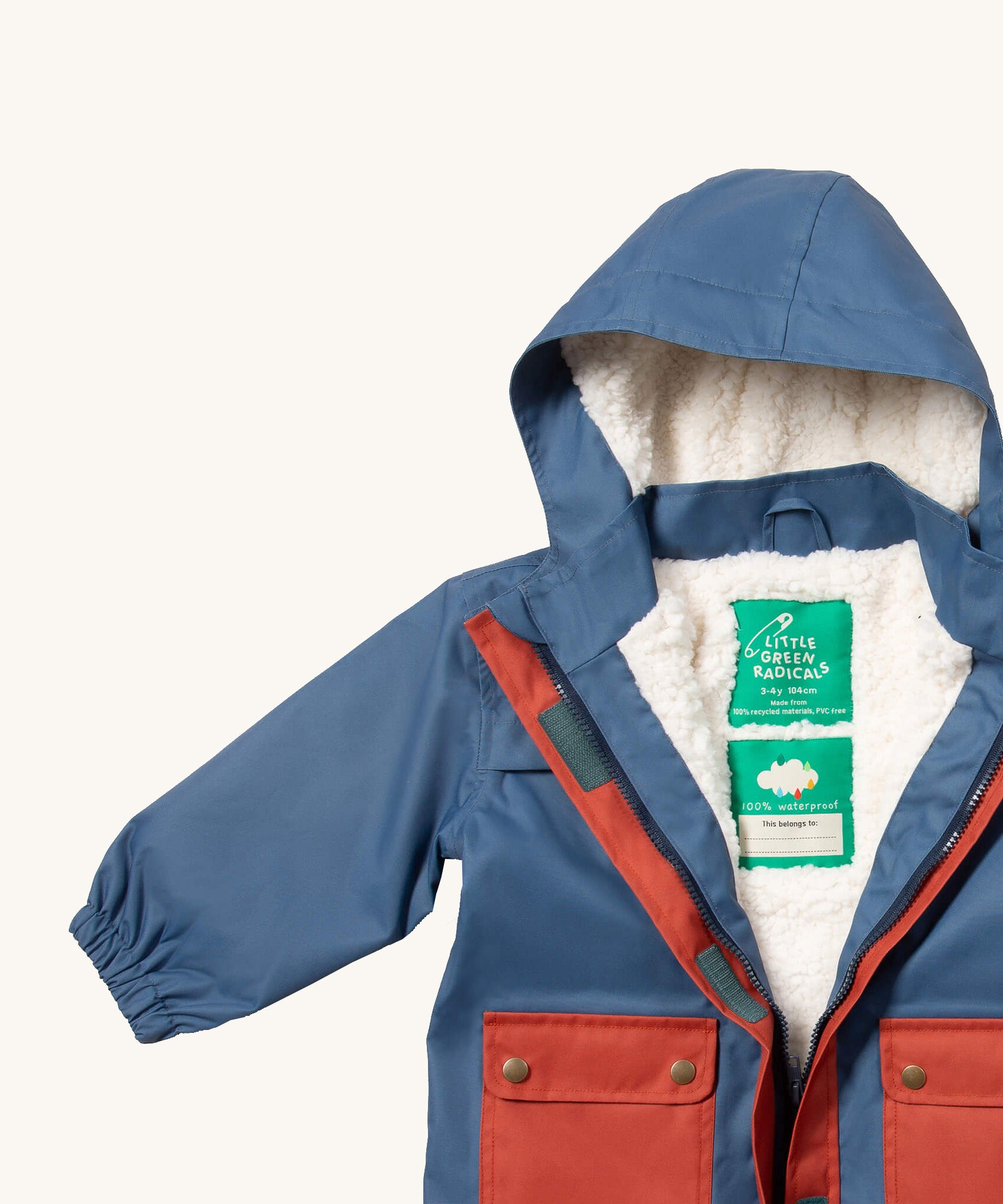 A close up of the Little Green Radicals waterproof coat in moonlight blue Showing the sherpa fleece liner and name patch detail on blue recycled polyester fabric