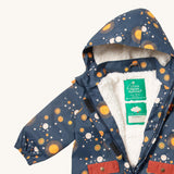 A close up of the Little Green Radicals waterproof coat in night moon showing the hood detail with sherpa fleece liner and name patch detail on navy recycled polyester fabric