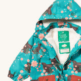A close up of the Little Green Radicals waterproof coat in winter rabbits showing the hood detail with sherpa fleece liner and name patch detail on turquoise recycled polyester fabric