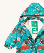 A close up of the Little Green Radicals waterproof coat in winter rabbits showing the hood detail with sherpa fleece liner and name patch detail on turquoise recycled polyester fabric