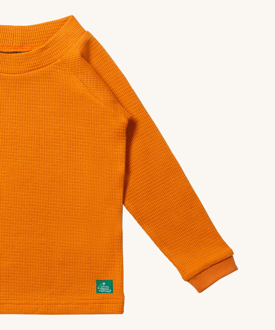 A close up of LGR Long Sleeve Waffle Top - Golden Ochre showing the waffle texture detail on yellow organic cotton fabric
