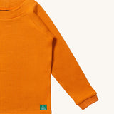 A close up of LGR Long Sleeve Waffle Top - Golden Ochre showing the waffle texture detail on yellow organic cotton fabric