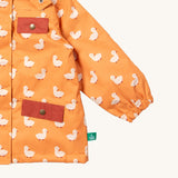 A close up of the Little Green Radicals waterproof coat in gold ducks Showing the elasticated cuff detail and red side and chest pocket on yellow recycled polyester fabric
