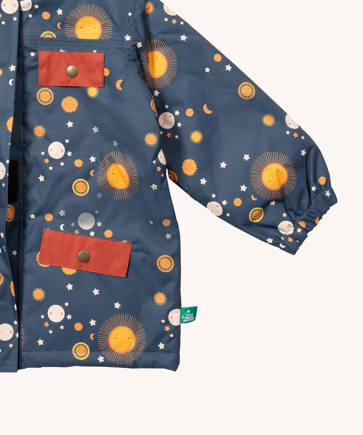 A close up of the Little Green Radicals waterproof coat in night moon. Showing the elasticated cuff detail and red side and chest pocket detail on navy recycled polyester fabric