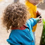 A child wearing the Little Green Radicals From One To Another Deep Blue Colour Block Knitted Cardigan. This organic cotton cardigan is part of a wide range of organic cotton, Fairtrade children's clothing and outerwear available here at Babipur.