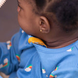 A close up of a baby wearing the Little Green Radicals Blue Rainbows Zip Organic Babygrow. The close up shows the yellow coloured cotton zip guard on the neck of the babygrow. Little green Radicals have a wide range of organic cotton, Fairtrade clothing and outerwear for babies and children available here at Babipur.