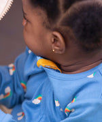 A close up of a baby wearing the Little Green Radicals Blue Rainbows Zip Organic Babygrow. The close up shows the yellow coloured cotton zip guard on the neck of the babygrow. Little green Radicals have a wide range of organic cotton, Fairtrade clothing and outerwear for babies and children available here at Babipur.