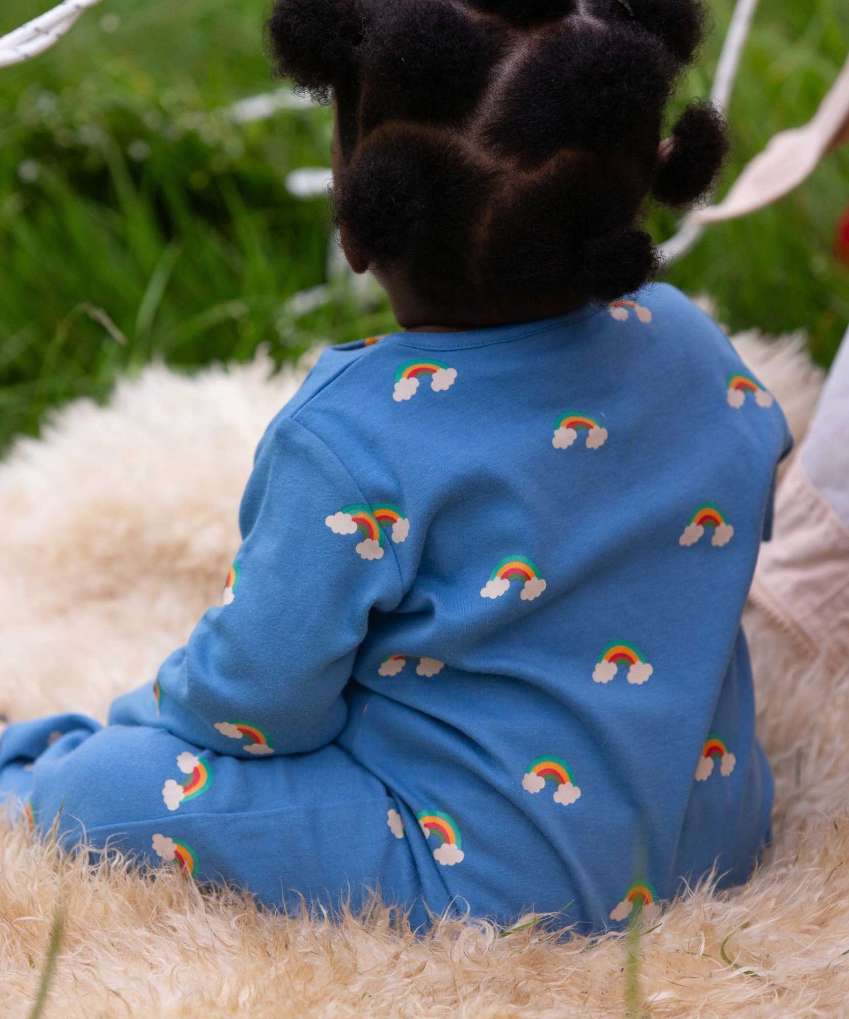A baby wearing the Little Green Radicals Blue Rainbows Zip Organic Babygrow. The baby is facing away from the camera. Little green Radicals have a wide range of organic cotton, Fairtrade clothing and outerwear for babies and children available here at Babipur.