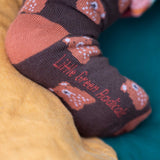 A close up of the Little Green Radicals brown teddy bear organic cotton socks on a child's feet. These socks are part of a wide range of organic cotton clothing and accessories for children available here at Babipur.