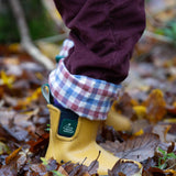 A close up of a child wearing the Little Green Radicals Chocolate brown Cord Lined Trousers with yellow gold wellington boots. These trousers are part of a wide range of organic cotton clothing for children available here at Babipur.
