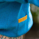 A close up of the pocket with a child wearing the Little Green Radicals From One To Another Deep Blue Colour Block Knitted Cardigan. This organic cotton cardigan is part of a wide range of organic cotton, Fairtrade children's clothing and outerwear available here at Babipur.
