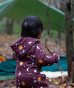 A view of the back of a child wearing the Little Green Radicals Organic Cotton Flying Birds Quilted Snug Suit. A maroon brown coloured suit with an all over print featuring flying birds, stars, moon and  sun. This snug suit is a part of a wide range of organic cotton clothing for children available here at Babipur.