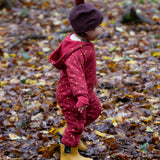 A child wearing the Little Green Radicals Organic Cotton Quilted Snug Suit with a Red Stars design. This snug suit is a part of a wide range of organic cotton clothing for children available here at Babipur.