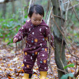 A child wearing the Little Green Radicals Organic Cotton Flying Birds Quilted Snug Suit. A maroon brown coloured suit with an all over print featuring flying birds, stars, moon and  sun. This snug suit is a part of a wide range of organic cotton clothing for children available here at Babipur.