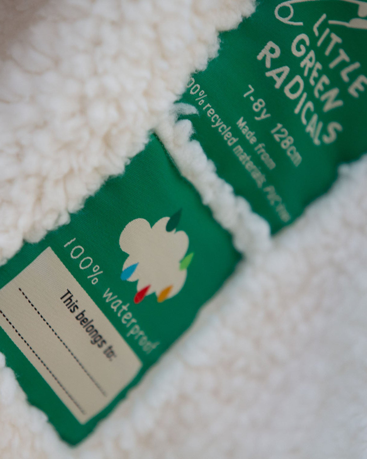 Two little green radicals labels on a white textured surface, with one label partially obscured.