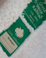 Two little green radicals labels on a white textured surface, with one label partially obscured.
