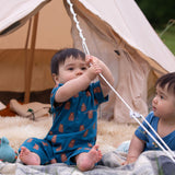 A child sitting in front of a bell tent wearing the Little Green Radicals Teddy Bears Organic Cotton Shortie Romper.