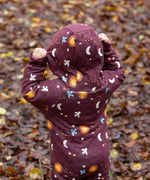 A child wearing the Little Green Radicals Organic Cotton Flying Birds Quilted Snug Suit. The child is facing away from the camera and is wearing the hood up.
A maroon brown coloured suit with an all over print featuring flying birds, stars, moon and  sun. This snug suit is a part of a wide range of organic cotton clothing for children available here at Babipur.