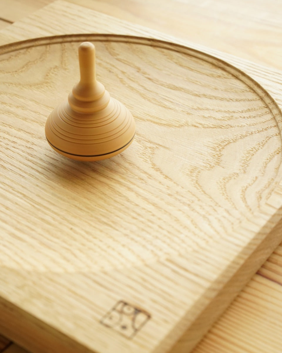 Mader kids classic wooden spinning top toy on a wooden Mader spinning top plate