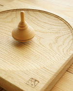 Mader kids classic wooden spinning top toy on a wooden Mader spinning top plate