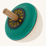 A wooden flower egg Mader spinning top with a green painted and  a yellow cut out design on the top on a cream background.