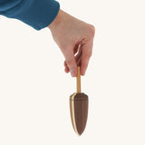 A wooden Mader goliath spinning top held by a hand on a cream background.