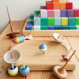 Mader wooden spinning tops on a Mader spinning plate next to a Grimms Large Stepped Pyramid