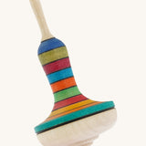 A wooden Mader manolette spinning top with a rainbow design on a cream background.