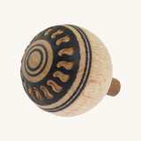 A wooden Mader Oriental turn over spinning top with a cut out pattern design on the bottom on a cream background.