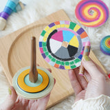 A brightly coloured Mader cardboard disc seen next to the wooden So and So spinner.