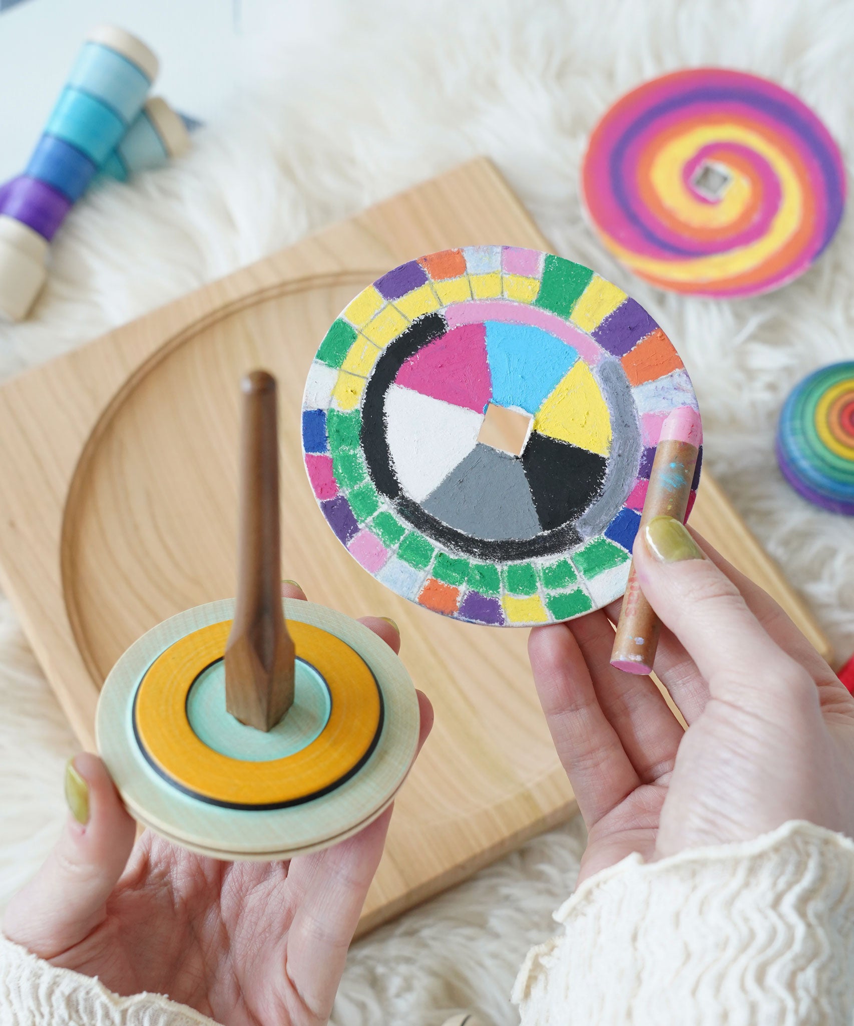 A brightly coloured Mader cardboard disc seen next to the wooden So and So spinner.