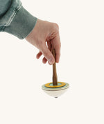 A hand holding the Mader 'So And So' DIY wooden spinning top