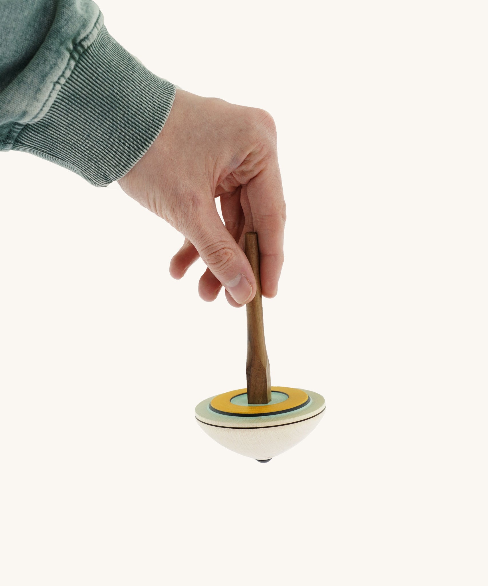 A hand holding the Mader 'So And So' DIY wooden spinning top
