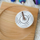 A Mader monochrome coloured disc placed on the so and so spinner. The spinner can be seen spinning in motion on a wooden spinning plate.